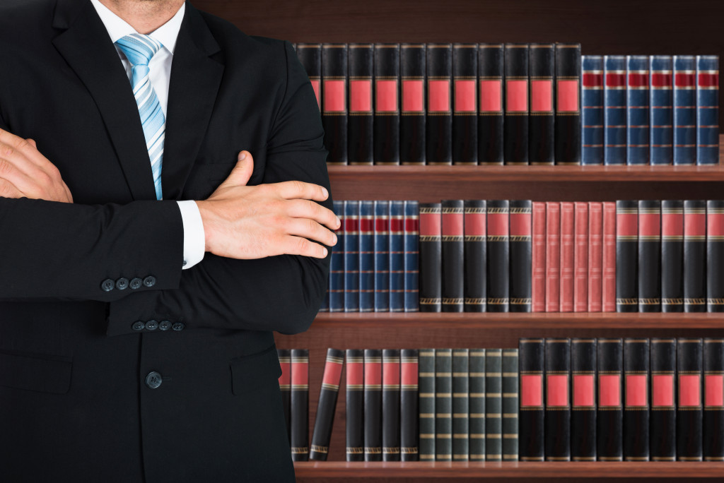 A lawyer with folded hands and books in the background