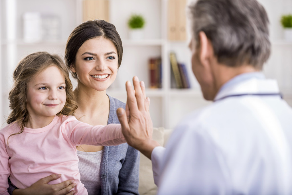 a little girl giving a high-five to doctor 