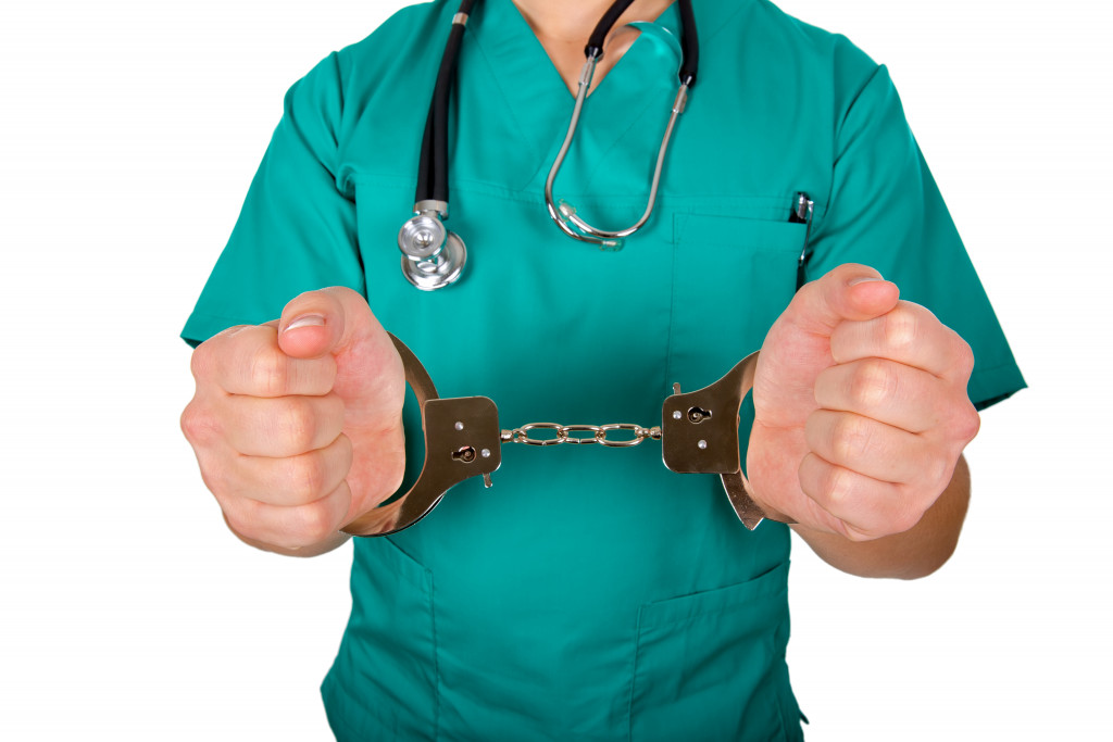 a doctor wearing stethoscope while hands in handcuffs