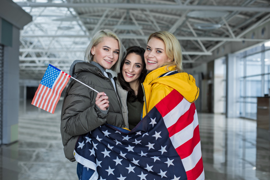 three female companions with US flag in the airport